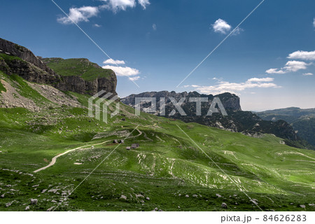 Amaizing view on Durmitor mountains, National Park, Mediterranean, Montenegro, Balkans, Europe. Bright summer view from Sedlo pass. The road near the house in the mountains. Amaizing view on Durmitor mountains, National Park, Mediterranean, Montenegro, Balkans, Europe. Bright summer view from Sedlo pass. The road near the house in the mountains. 84626283