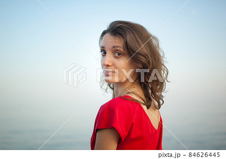 Young girl in red dress on the sea and blue background, summertime, travelling concepts Young girl in red dress on the sea and blue background, summertime, travelling concepts 84626445