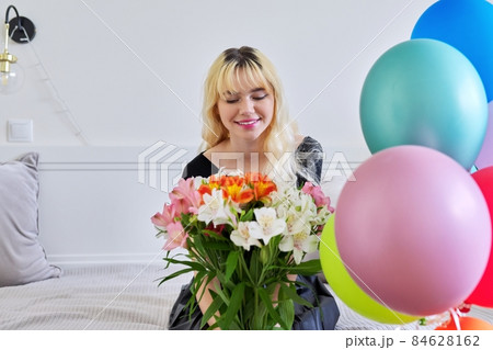 Portrait of birthday girl teenager with bouquet of flowers and balloons at home Portrait of birthday girl teenager with bouquet of flowers and balloons at home 84628162