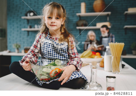 Little girl eating in the kitchen with granparents Little girl eating in the kitchen with granparents 84628811