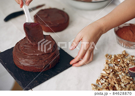 Chef spreads the cake with chocolate glaze. 84628870