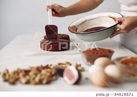 Chef spreads the cake with chocolate glaze. 84628871
