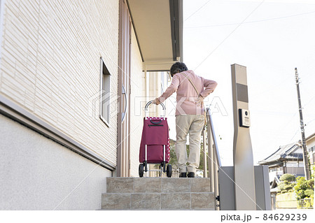 玄関前で腰をおさえるシニア女性の後ろ姿 84629239