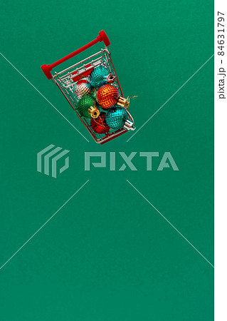 Grocery cart with Christmas balls toys on a blue-green simple background. Flat lay. Save the space. Postcard Template Grocery cart with Christmas balls toys on a blue-green simple background. Flat lay. Save the space. Postcard Template 84631797
