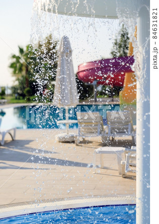 Sun loungers stand by the pool with a children's waterfall fountain 84631821
