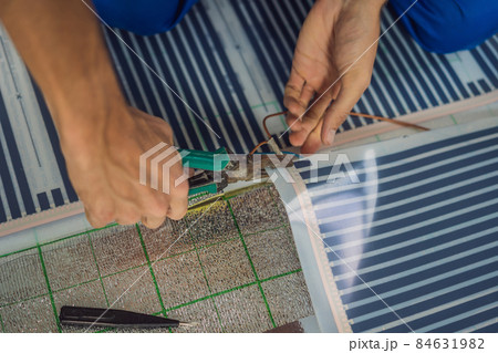 Master installs film warm floor in the room. Floor heating installation Master installs film warm floor in the room. Floor heating installation 84631982