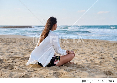 Young relaxed woman sitting in lotus position on beach, morning sea nature Young relaxed woman sitting in lotus position on beach, morning sea nature 84631983