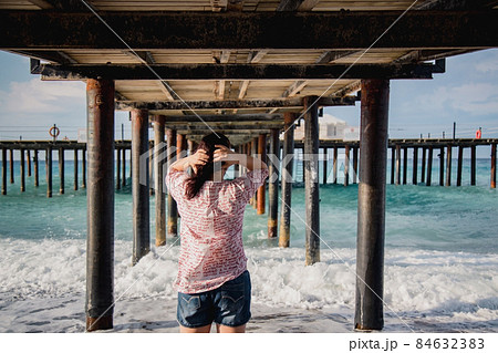 Turkey, Mediterranean Sea. Young woman turned away from the camera, running away from the waves under a wooden pier Turkey, Mediterranean Sea. Young woman turned away from the camera, running away from the waves under a wooden pier 84632383