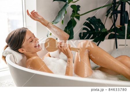 Beautiful young woman singing in the bathtub while relaxing at luxury spa resort 84633780