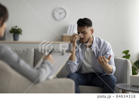 Depressed middle eastern guy crying at psychotherapist's office, seeking professional help, sharing his problems Depressed middle eastern guy crying at psychotherapist's office, seeking professional help, sharing his problems 84634318