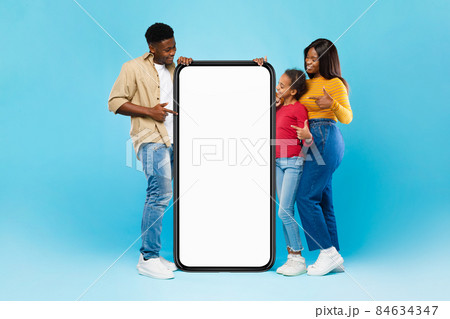 Black family pointing at big white empty smartphone screen, mock-up Black family pointing at big white empty smartphone screen, mock-up 84634347