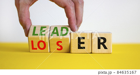 Loser or leader symbol. Businessman turns cubes and changes the word 'loser' to 'leader'. Beautiful yellow table, white background. Business and loser or leader concept. Copy space. Loser or leader symbol. Businessman turns cubes and changes the word 'loser' to 'leader'. Beautiful yellow table, white background. Business and loser or leader concept. Copy space. 84635167