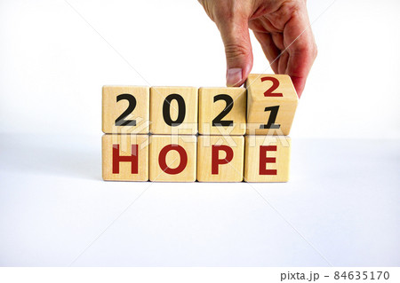 2022 hope new year symbol. Businessman turns a wooden cube and changes words 'Hope 2021' to 'Hope 2022'. Beautiful white background, copy space. Business, 2022 hope new year concept. 2022 hope new year symbol. Businessman turns a wooden cube and changes words 'Hope 2021' to 'Hope 2022'. Beautiful white background, copy space. Business, 2022 hope new year concept. 84635170