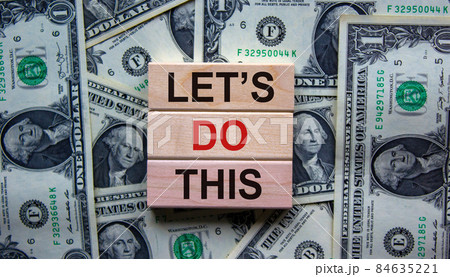 Blocks tower with words 'lets do this' on beautiful background from dollar bills. Copy space. Business concept. Blocks tower with words 'lets do this' on beautiful background from dollar bills. Copy space. Business concept. 84635221