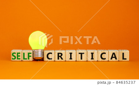 Critical or self-critical symbol. Cubes with words 'Self-critical or critical'. Yellow light bulb. Beautiful orange background. Psychology, critical or self-critical and business concept. Copy space. Critical or self-critical symbol. Cubes with words 'Self-critical or critical'. Yellow light bulb. Beautiful orange background. Psychology, critical or self-critical and business concept. Copy space. 84635237