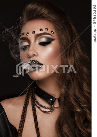 Portrait of a beautiful woman in a rock style image with creative makeup and hairstyle. Portrait of a beautiful woman in a rock style image with creative makeup and hairstyle. 84635293