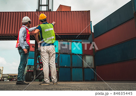 Industrial worker works with co-worker at overseas shipping container yard 84635445