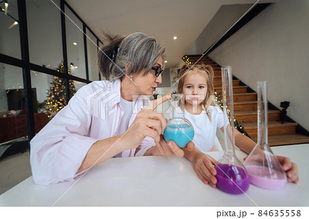 Attentive old grandma assist grandkid in funny scientific research 84635558