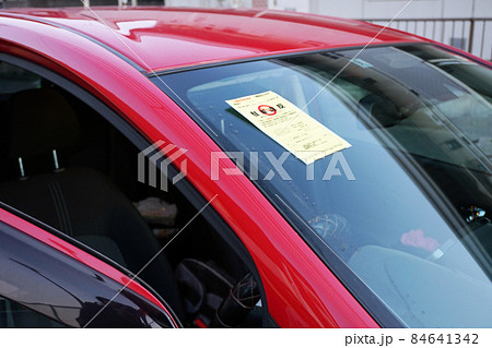 駐車違反のステッカーが赤い車に貼られている 駐車違反のステッカーが赤い車に貼られている 84641342