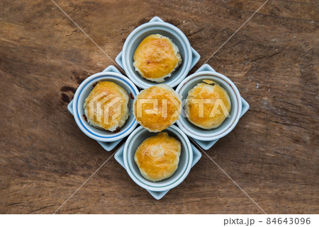 A traditional asian pastry or Tao Sor on rustic wooden table. Chinese sweet pastry filled with mung bean paste, taro, and salted egg. A traditional asian pastry or Tao Sor on rustic wooden table. Chinese sweet pastry filled with mung bean paste, taro, and salted egg. 84643096
