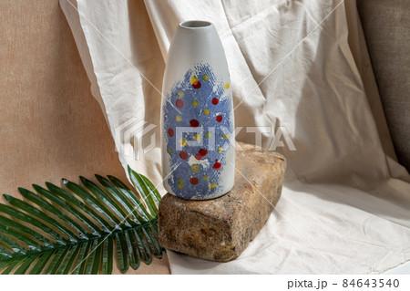 Blue and White handmade ceramic vase on white textured table cloth. 84643540