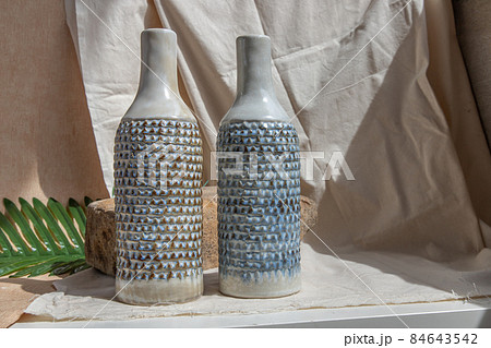 Two white and blue handmade ceramic vases on white textured table cloth. Two white and blue handmade ceramic vases on white textured table cloth. 84643542