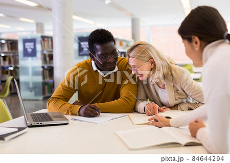 Students sitting in library, working with professor 84644294