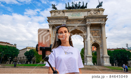 Travel influencers Milan island. Paint building house in Europe Milano. Photographer blogger girl with smartphone in Piazza del Duomo, Cathedral Square. Traveling and freelancing, modern lifestyle. Travel influencers Milan island. Paint building house in Europe Milano. Photographer blogger girl with smartphone in Piazza del Duomo, Cathedral Square. Traveling and freelancing, modern lifestyle. 84645049