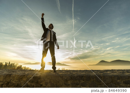 Triumphant businessman greeting a new day Triumphant businessman greeting a new day 84649390