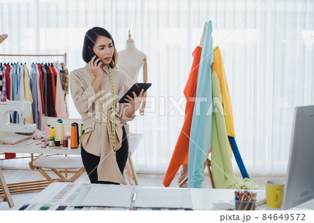 Professional fashion designer talking on phone with the customer and taking of the work details. 84649572