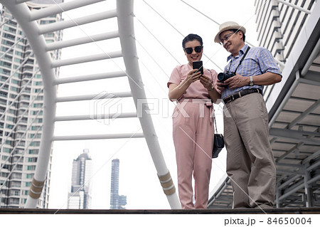 Senior Asian couple playing mobile outdoors. 84650004