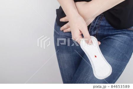 Hypomenorrhea. The woman shows a gynecological pad with a small drop of blood on it. Concept of small amounts during scanty menstruation. Complaints of pain and strange cycle. Diseases in gynecology 84653589