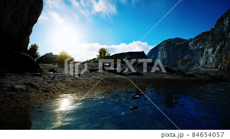 sandy beach in bay surrounded by steep mountains in sunset 84654057