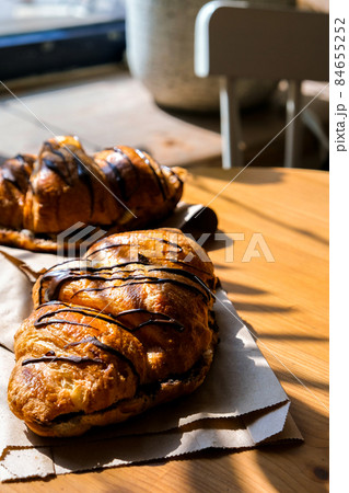 Fresh and tasty Croissants with chocolate butter and banana on crumpled paper. Breakfast at cafe. Morning routine. French pastry. Baked bun. Oven croissant. Sunlight street cafe 84655252