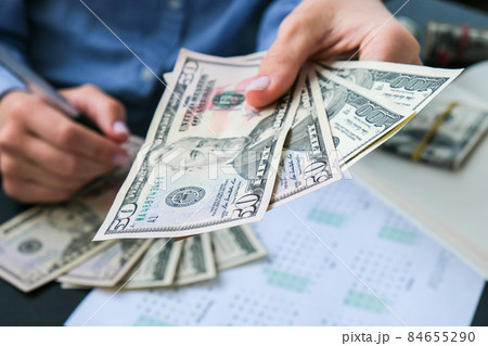 Business Woman Displaying a Spread of Cash US dollars. Close-up. Income and Business concept. Venality, bribe, corruption concept. Hand giving money. Millennial candid authentic female hands counting 84655290