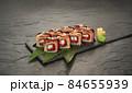 sushi rolls with tuna salmon eel unagi and avocado on a black stone plate. 84655939