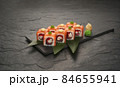 sushi rolls with tuna salmon eel unagi and avocado on a black stone plate. 84655941