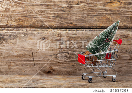 Shopping cart with a Christmas tree on a wooden background. 84657293