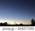 夜空に浮かぶ三日月と夕暮れの街並みのシルエット風景 84657390