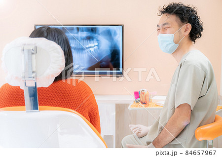 歯科医院で患者さんに模型で説明するドクターの様子 84657967