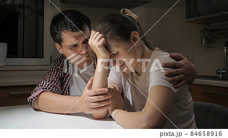 Yougn crying woman suffering from depression and problems sitting on kitchen with her husband 84658916