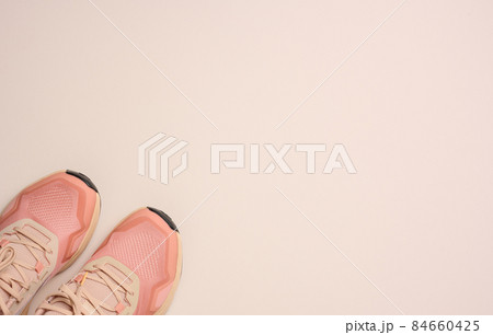 pair of pink textile sneakers on beige background, top view 84660425