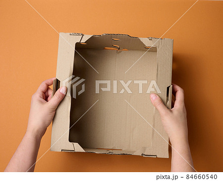 female hands are holding an empty open box of brown cardboard, top view, concept of packing things female hands are holding an empty open box of brown cardboard, top view, concept of packing things 84660540