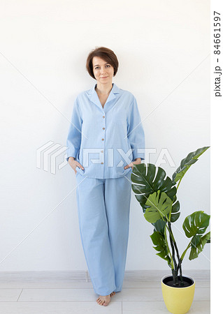 Young attractive woman dressed in beautiful colorful pajama posing as a model in her living room. Comfortable sleepwear, home relaxation and female fashion concept. 84661597