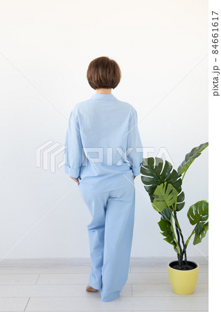 Back view of woman dressed in beautiful colorful pajama posing as a model in her living room. Comfortable sleepwear, home relaxation and female fashion concept. Back view of woman dressed in beautiful colorful pajama posing as a model in her living room. Comfortable sleepwear, home relaxation and female fashion concept. 84661617
