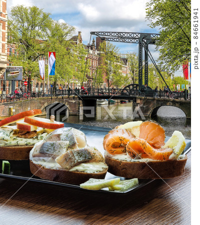 Amsterdam city with fishplate (salomon and codfish sandwiches) against tourboat on canal in Netherlands Amsterdam city with fishplate (salomon and codfish sandwiches) against tourboat on canal in Netherlands 84661941