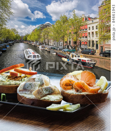 Amsterdam city with fishplate (salomon and codfish sandwiches) against tourboat on canal in Netherlands Amsterdam city with fishplate (salomon and codfish sandwiches) against tourboat on canal in Netherlands 84661943