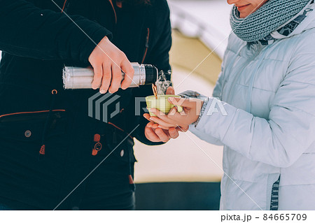 guy pour hot coffee to his girlfriend in green cup. winter hike theme 84665709