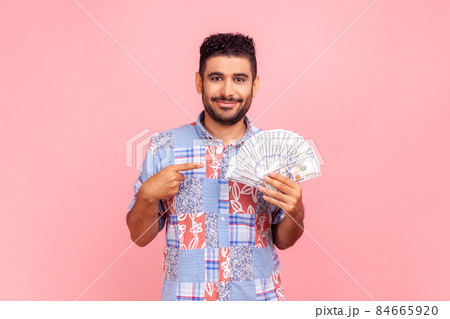 I have big money. Portrait of rich young adult man pointing at dollar banknotes and looking with happy expression, financial savings. Indoor studio shot isolated on pink background. 84665920