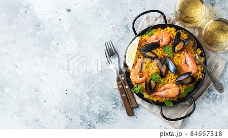 Traditional spanish seafood paella in pan with chickpeas, shrimps, mussels, squid on light grey concrete background. Top view with copy space 84667318